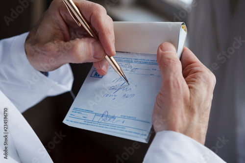 A doctor writing a prescription on a blue prescription pad. photo