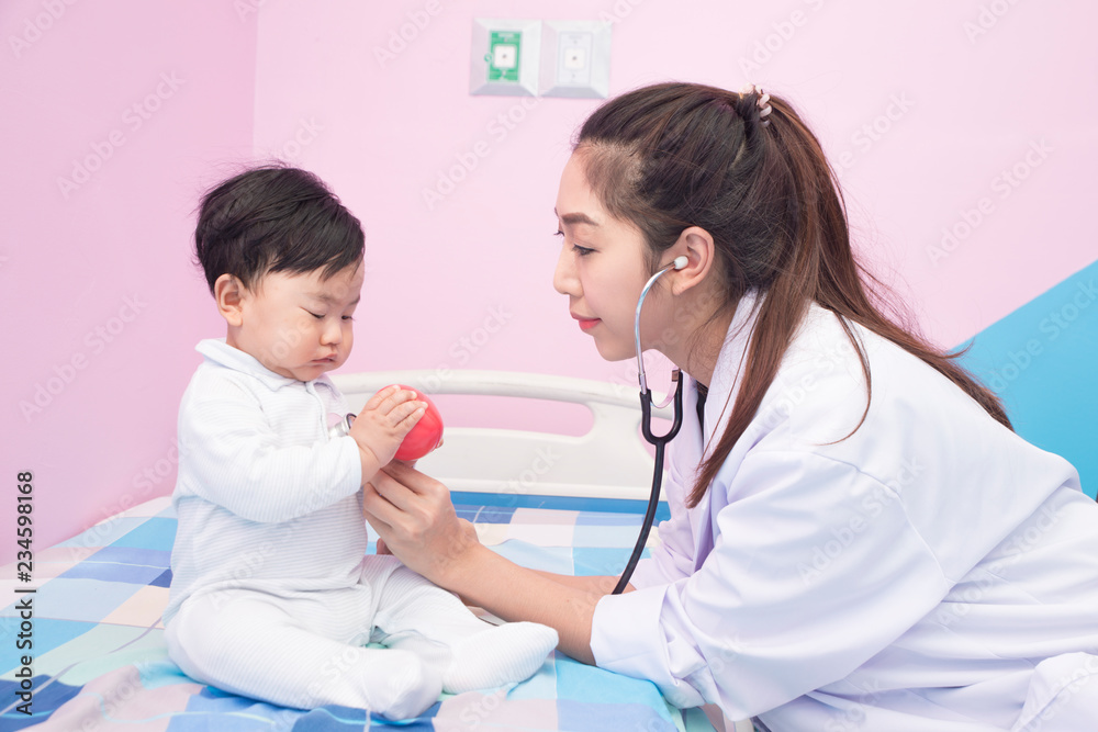 Pediatrician Doctor examines Asian baby girl. Doctor using a stethoscope to listen to infant's chest checking heartbeat or lung. Medical and healthcare concept Pediatrician Doctor examines Asian baby girl. Doctor using a stethoscope to listen to infant's chest checking heartbeat or lung. Medical and healthcare concept