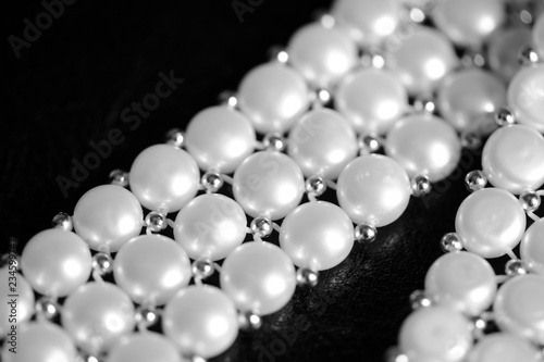 White pearl necklace on a dark background close up. Black and white