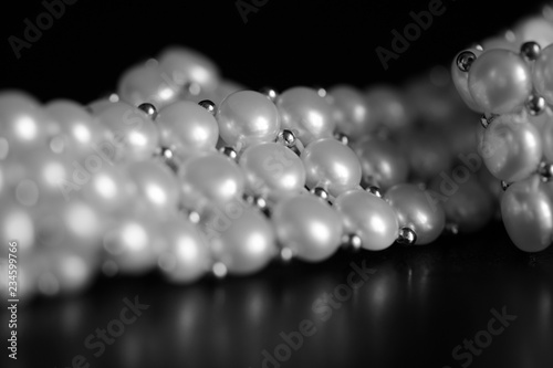 White pearl necklace on a dark background close up. Black and white