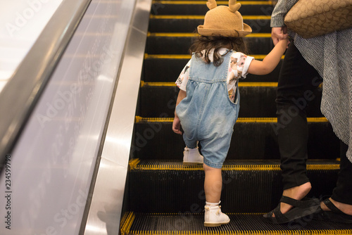 Little Asian girl use escalators with her mother in the shopping mall, Kid is prohibited to use the escalator alone because it is very dangerous.
