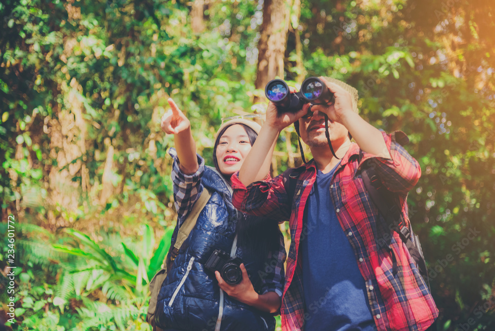 Attractive young couple hiking in the forest using binoculars. Attractive young couple hiking in the forest using binoculars.