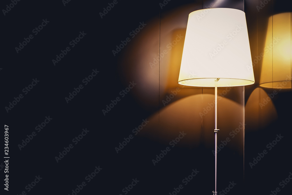 A lamp with rounded corners lit up on a wall surrounded by a deep dark shadow,Vintage effect style picture. A lamp with rounded corners lit up on a wall surrounded by a deep dark shadow,Vintage effect style picture.