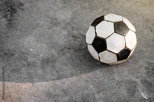 Old football. Black and white soccer ball is placed on the concrete ground.