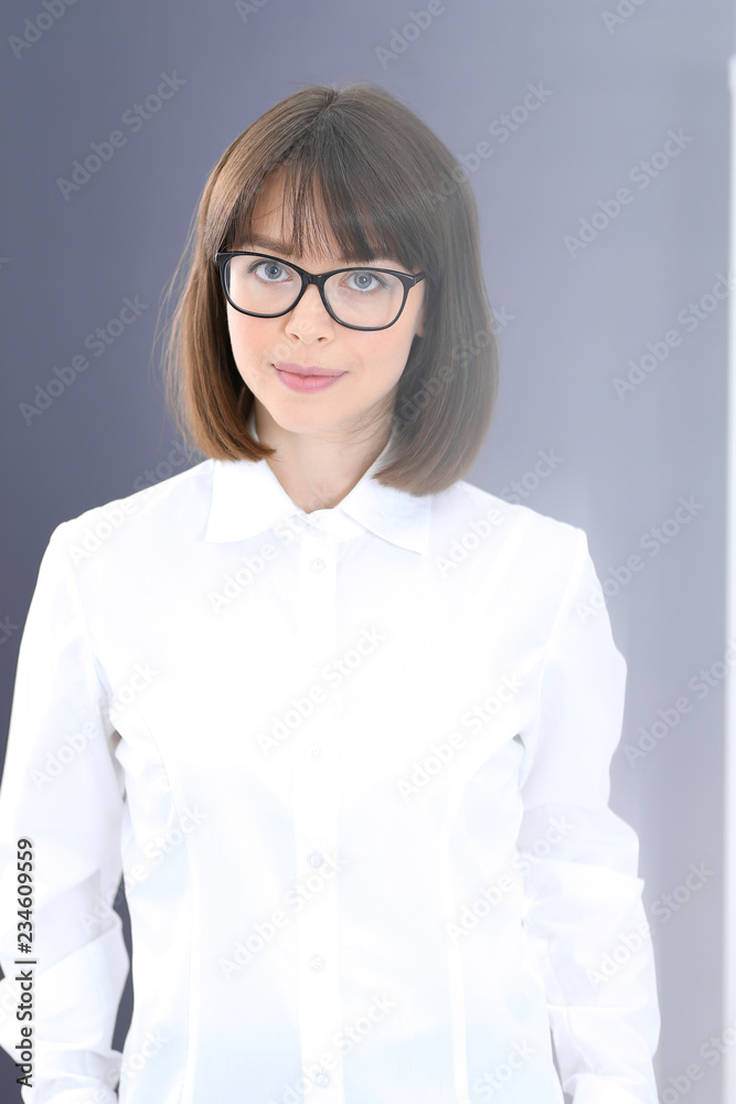 Young brunette business woman looks like a student girl working in office. Caucasian  girl standing straight