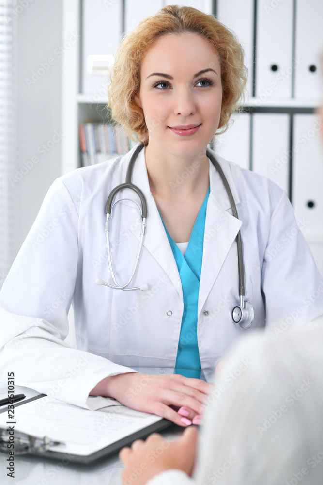 Happy blonde female doctor and patient discussing medical examination results. Medicine, healthcare and help concept Happy blonde female doctor and patient discussing medical examination results. Medicine, healthcare and help concept