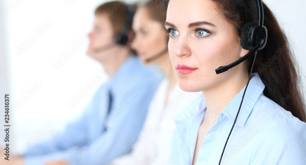 Call center operators at work. Focus at business woman in headset Call center operators at work. Focus at business woman in headset