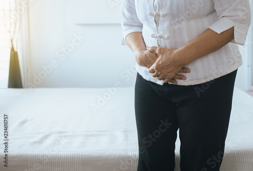 Elderly asian woman having painful stomachache on bedroom,Female suffering from abdominal pain while lying in bedroom