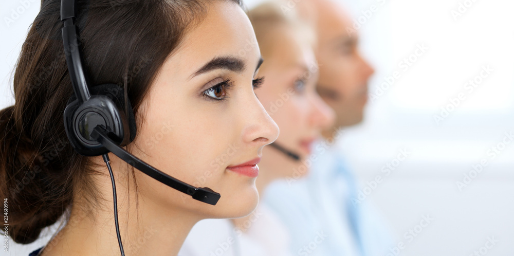 Call center operators at work. Focus at beautiful latin american woman in headset Call center operators at work. Focus at beautiful latin american woman in headset