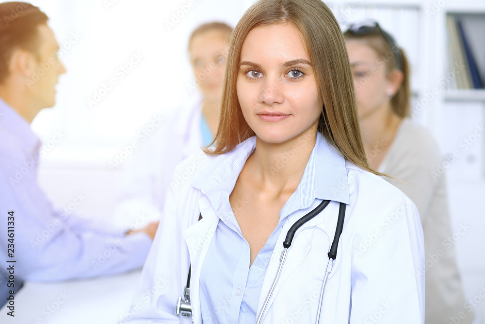 Happy doctor woman with medical staff at the background in hospital office Happy doctor woman with medical staff at the background in hospital office