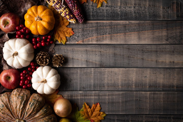 Top view of  Autumn maple leaves with Pumpkin, apple, corn and red berries on old wooden background. Thanksgiving day concept.