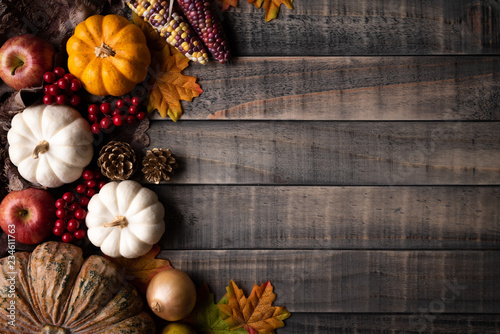 Top view of  Autumn maple leaves with Pumpkin, apple, corn and red berries on old wooden background. Thanksgiving day concept. photo