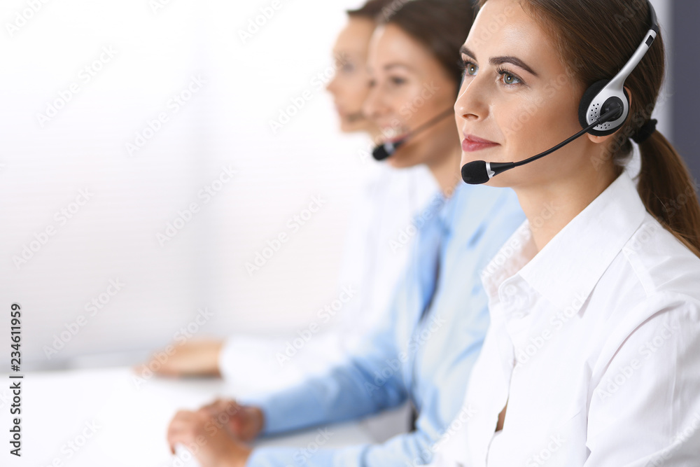 Call center. Group of operators at work. Focus at beautiful business woman in headset Call center. Group of operators at work. Focus at beautiful business woman in headset