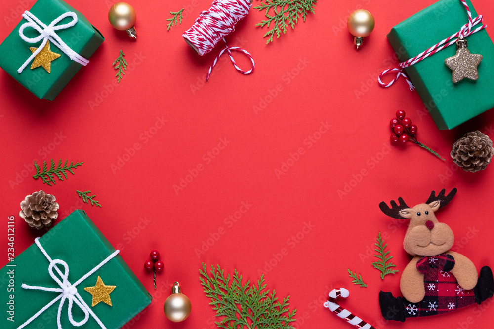 Christmas background concept. Top view of Christmas green gift box red sock with spruce branches, pine cones, red berries and bell on red background.