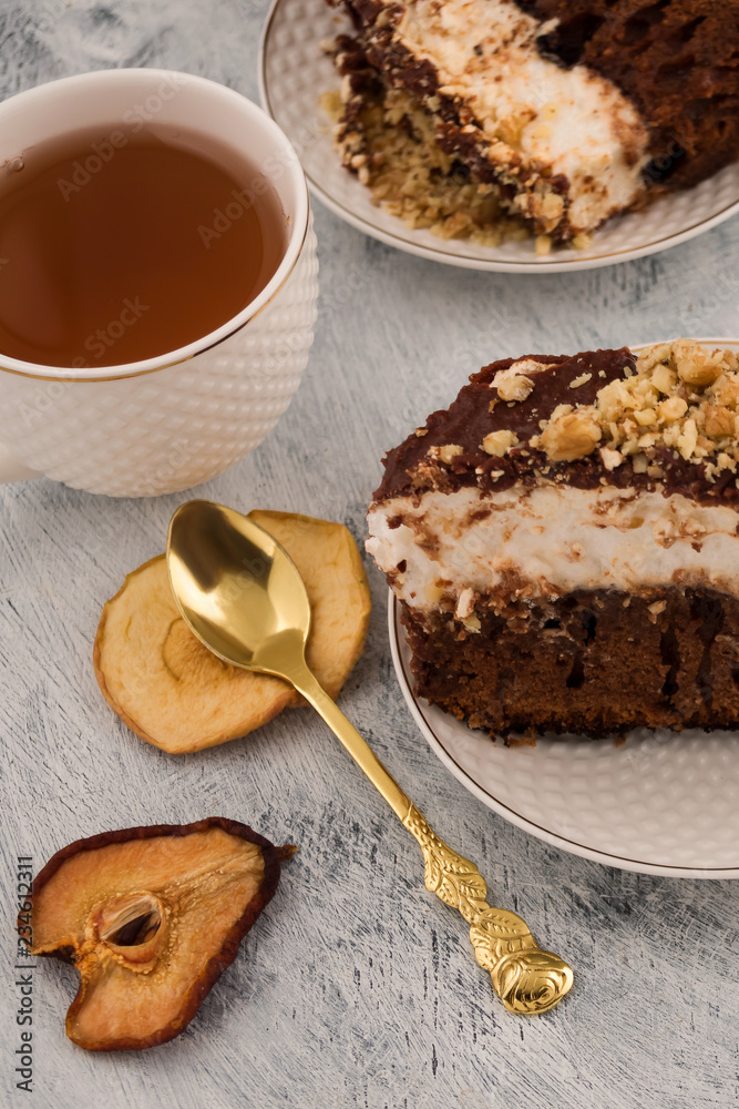 Chocolate dessert on plates. Teaspoon dried fruit slices. Tea in white mug. Vertical. Light background. Chocolate dessert on plates. Teaspoon dried fruit slices. Tea in white mug. Vertical. Light background.