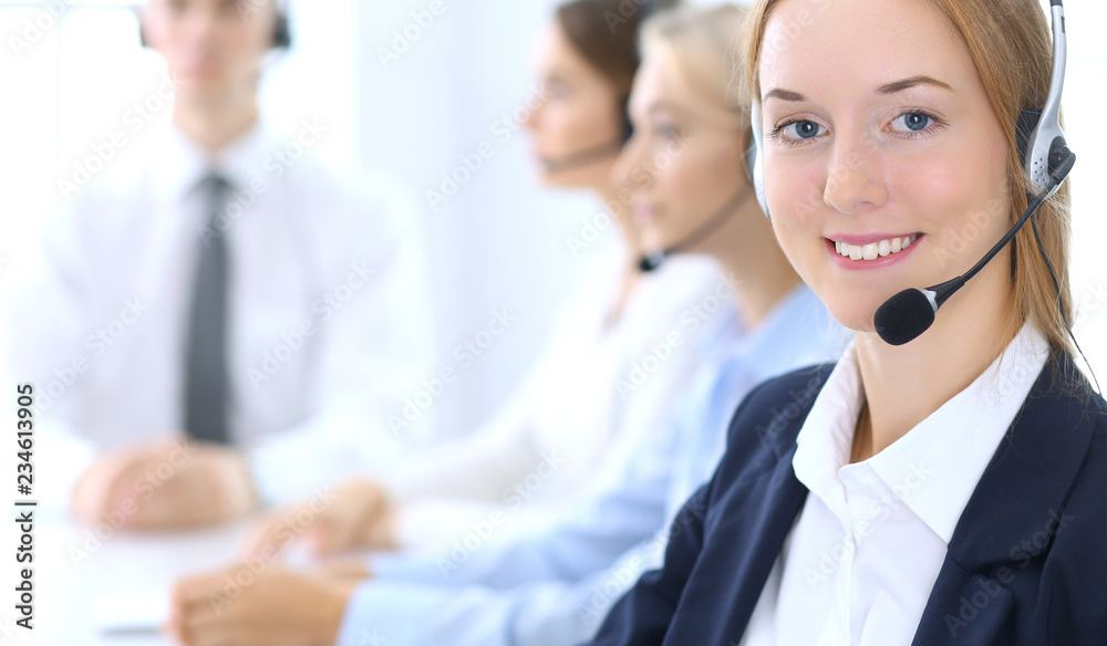 Call center. Group of operators at work. Focus at brunette business woman in headset Call center. Group of operators at work. Focus at brunette business woman in headset