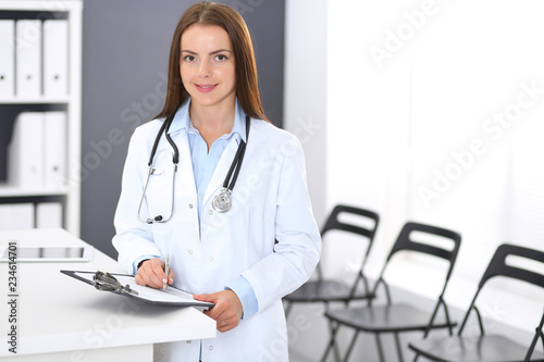 Doctor woman at work. Portrait of female physician standing near reception desk at clinic or emergency hospital. Medicine and healthcare concept