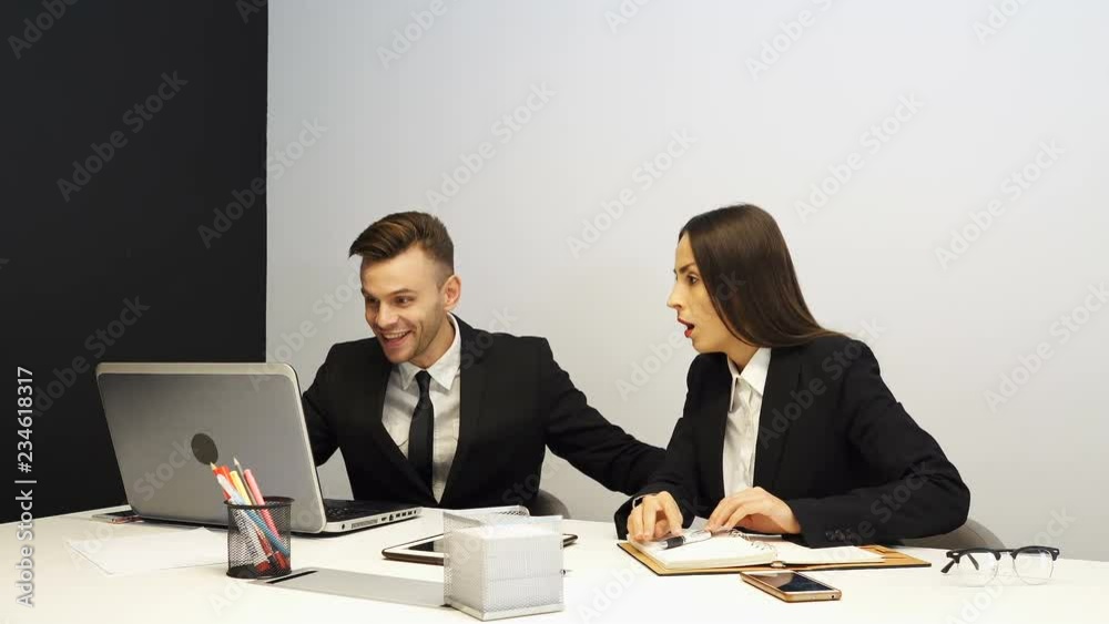 4K. Beautiful businesswoman and businessman smiles and rejoice good news from laptop. Bright positive emotions 4K. Beautiful businesswoman and businessman smiles and rejoice good news from laptop. Bright positive emotions