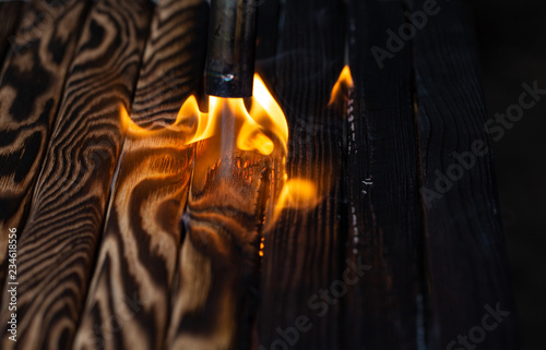 Charred wooden planks and fire. Background, texture. Flame. Wood processing.