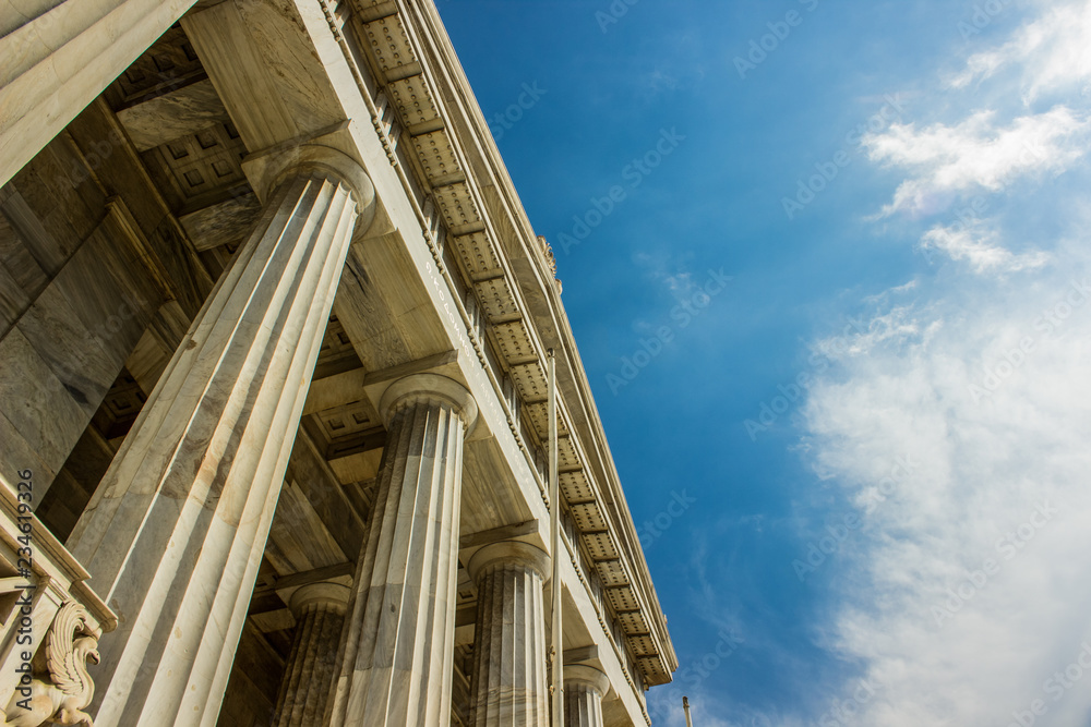 Roman architecture marble palace facade with columns foreshortening from below in contrast vivid blue sky background, copy space