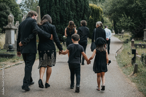 Fototapeta Grieving family walking through a cemetery