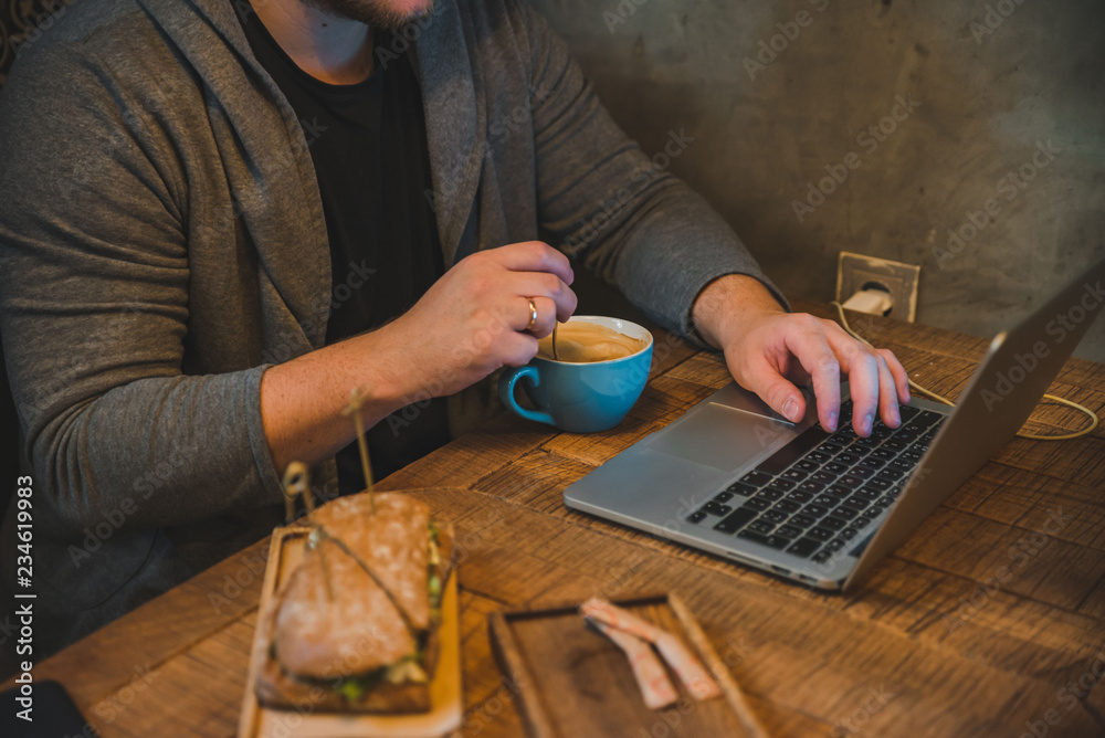 man hands working on laptop in cafe eating sandwich drinking coffee man hands working on laptop in cafe eating sandwich drinking coffee