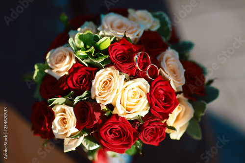 Flower wedding bouquet of white and red roses with golden bride hoops