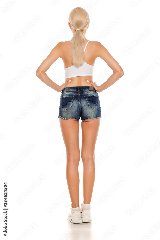 back view of young pretty blonde woman posing in short jeans on white background back view of young pretty blonde woman posing in short jeans on white background