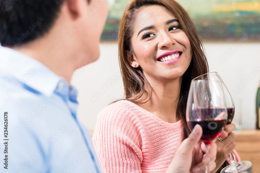 Smiling young woman toasting the red wine glass with her boyfriend Smiling young woman toasting the red wine glass with her boyfriend