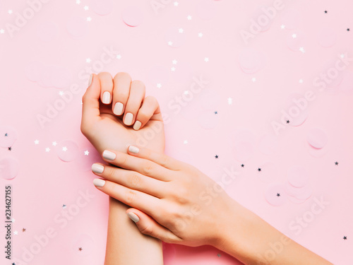 Beatiful female hands with stylish manicure on sparkling holiday background. Top view, flat lay.