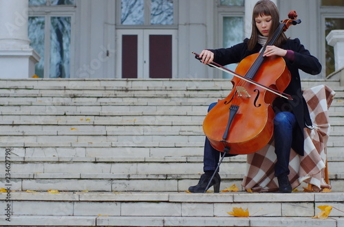 Canvas Print young woman playing cello on the steps of marble staircase of an ancient house