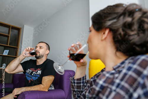 Beautiful couple posing on armchair with wineglass