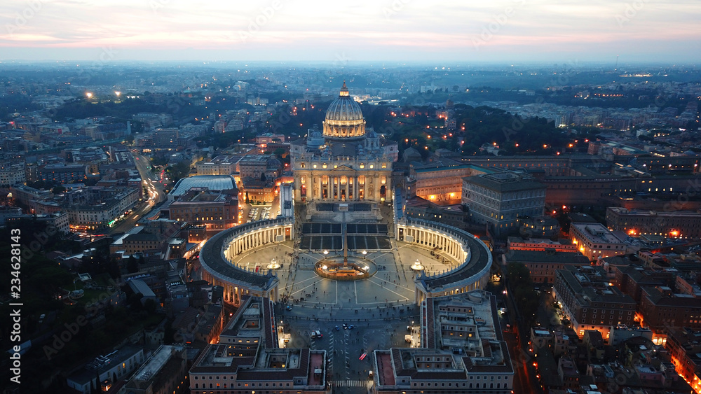 Aerial drone night view of Saint Peter's square in front of world's largest church - Papal Basilica of St. Peter's, Vatican -an elliptical esplanade created in the mid seventeenth century, Rome, Italy