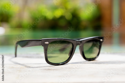 Black sunglasses next to swimming pool