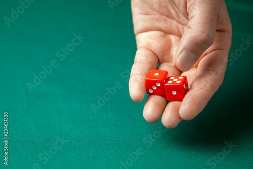 Man holds two red dices and throws them on green poker gaming table in casino. Concept of online gambling, winner or player. Copy space for text