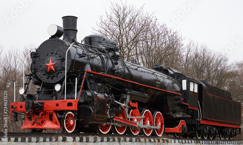 Front side view of old classic black soviet steam locomotive with red star on front