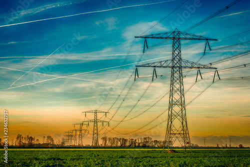 Quadro em tela High voltage towers with thick hanging power cables in a rural landscape in the