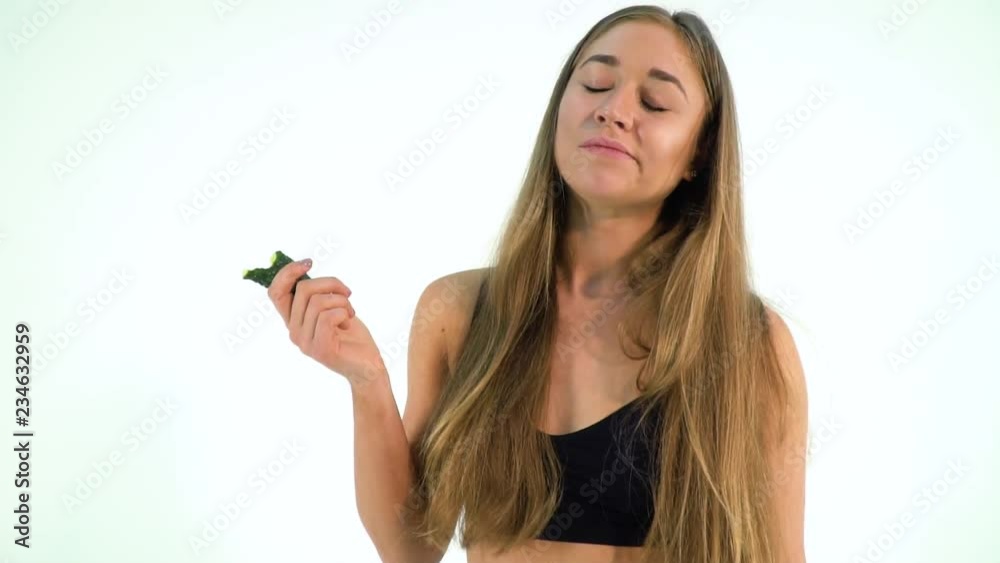 Fit blonde woman in sportswear eating a cucumber Fit blonde woman in sportswear eating a cucumber
