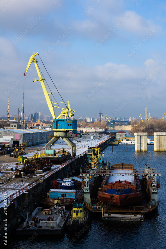 A barge in the river port and working cranes on the city background