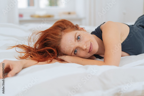Young redhead woman relaxing on her bed photo