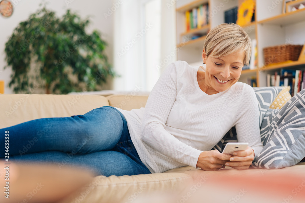 woman reclining on a sofa using a mobile woman reclining on a sofa using a mobile