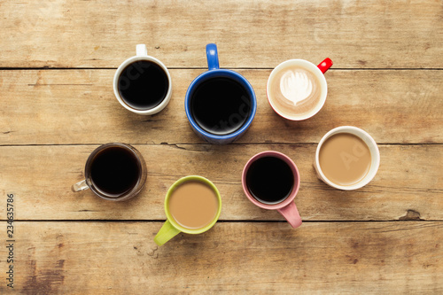 A lot of multicolored cups with coffee and coffee drinks on a wooden background. Concept breakfast with coffee, coffee with friends. Flat lay, top view