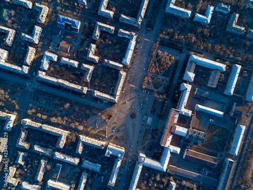 Aerial view of cityscape  top down drone shot  smooth rows of houses and streets with square in center  architectural ensembles, complexes with gardens and parks  street geometric pattern single style © Maria Shaytor