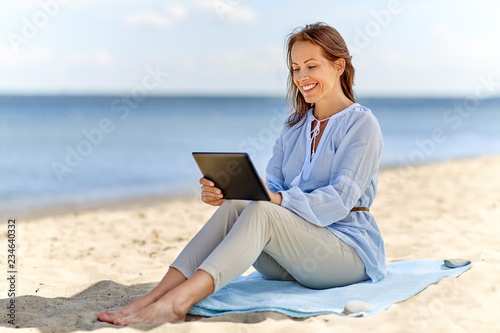 technology, people and leisure concept - happy smiling woman with tablet pc computer on summer beach © Syda Productions