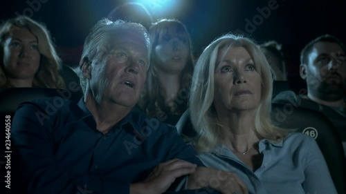 Older couple watching a scary film jump with fright.