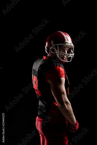 American football player in helmet standing against black