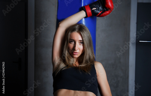 Girl in gloves in a sport hall next to a boxer pear