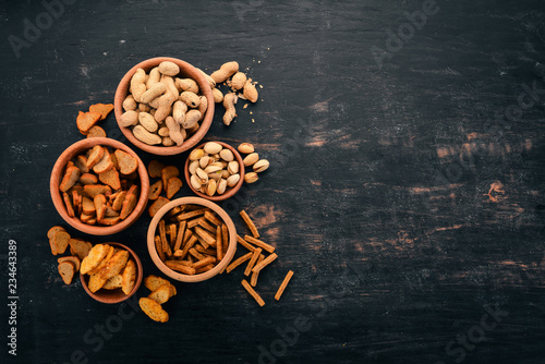 Snack for beer. Salted crackers, chips, nuts, peanuts, pistachios. On a wooden background. Free space for text. Top view. © Yaruniv-Studio