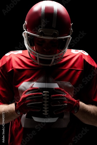 American football player with helmat looking at rugby ball photo