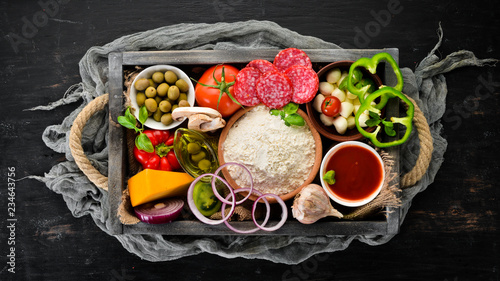 Ingredients for pizza in a wooden box. Top view. On a wooden background. Free copy space.